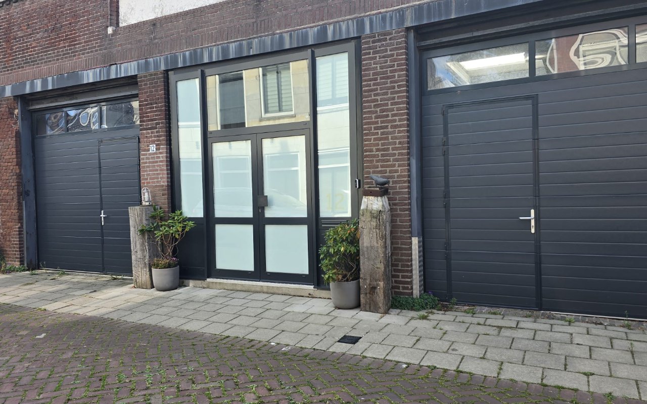 De voorgevel van BC Laserstudio aan de Nieuwstraat 12, met donkere garagedeuren en een glazen dubbele deur