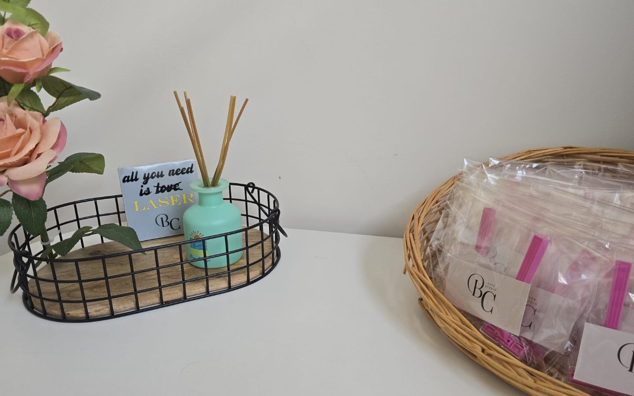 Rozen, een geurstokjesflesje en een mand met BC Laserstudio-cadeautasjes in de studio